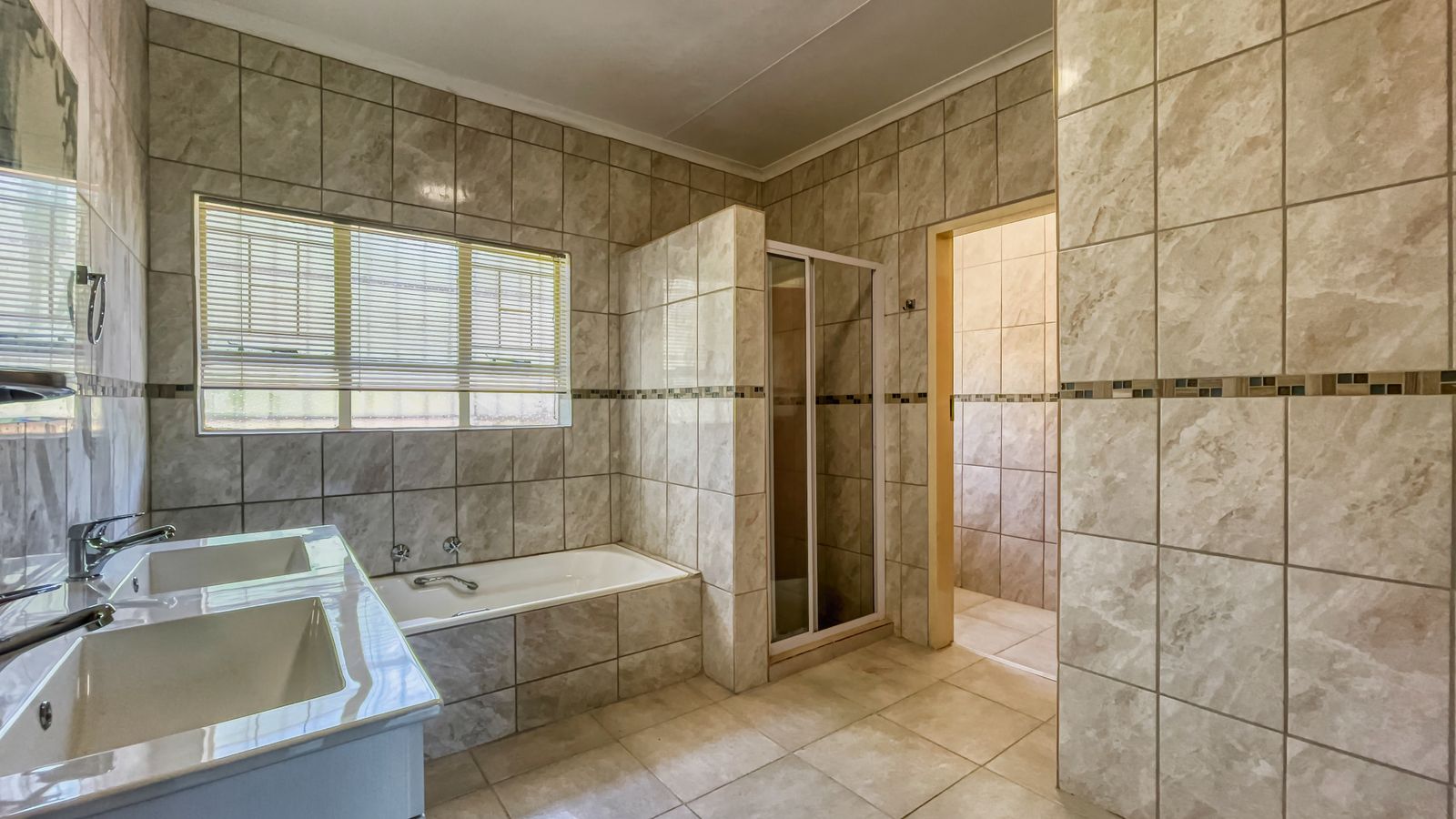 Baño con microcemento gris claro, ducha de obra y grifo negro mate en piso barcelonés reformado